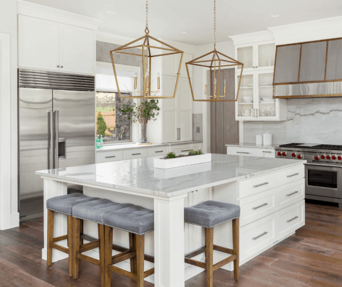 kitchen featuring white cabinets on the island with gold pendant lights and barstools with a blue fabric on top