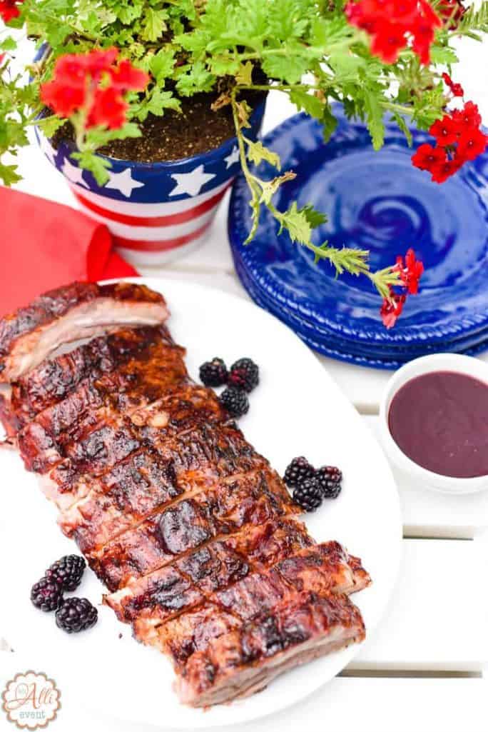 Slab of Grilled Ribs on a white table with an easy DIY centerpiece clay pot painted red, white and blue stripes with a red flower