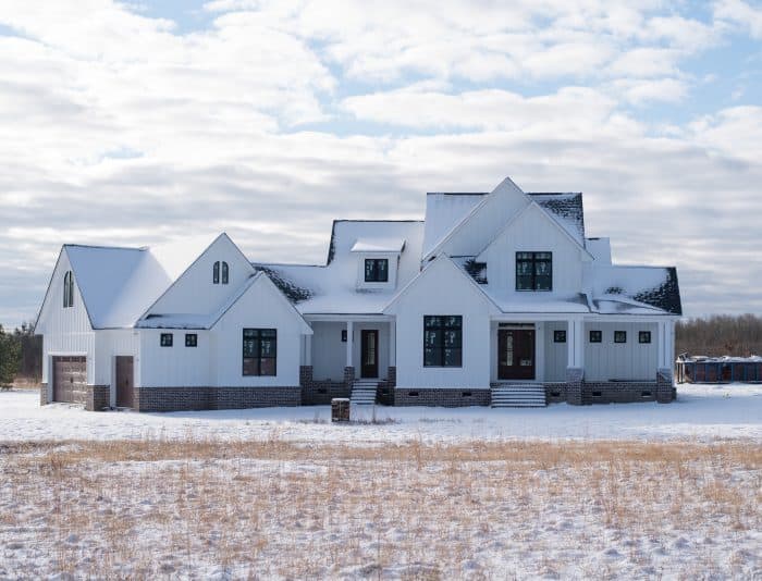 modern white farmhouse with snow on the ground