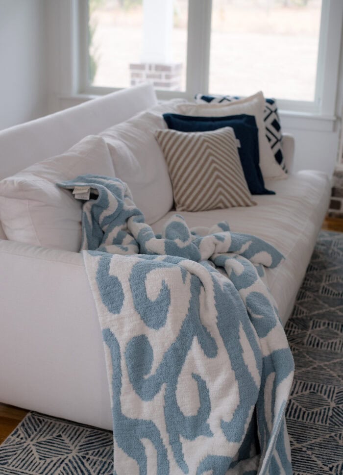 white sofa with a blue and white throw on one end and pillows on the other end.